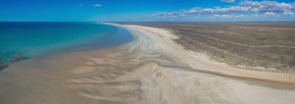 Aerial view of pristine eighty mile beach and serene indian ocean with blue sky and clouds, Cape Keraudren Coastal Reserve, Western Australia, Australia.