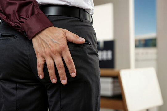 Male Boss hand touching male employee's butt in office