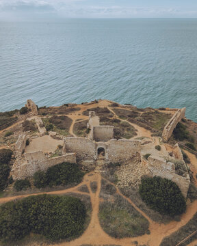 Aerial view of the historic ruins of Forte de Almadena on a scenic cliff by the tranquil ocean, Budens, Portugal.
