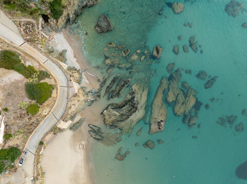 Aerial view of masua beach with beautiful cliffs and blue ocean waves, Iglesias, Italy.