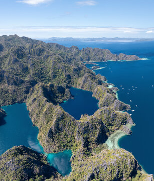 Aerial view of a beautiful tropical island with crystal clear water and lush green mountains, Banuang Daan, Coron, Palawan, Philippines.