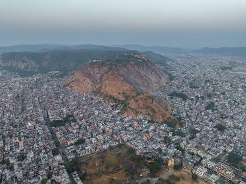 Aerial view of vibrant cityscape featuring Ganesh Ji Temple amidst bustling buildings and hills, Subhash Nagar, Jaipur, Rajasthan, India.