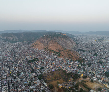 Aerial view of dense cityscape with beautiful rooftops and expansive mountains, Subhash Nagar, Jaipur, Rajasthan, India.
