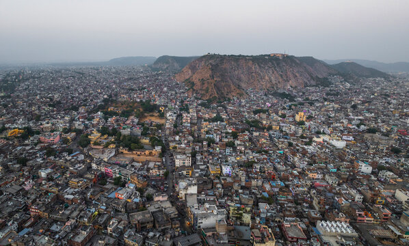 Aerial view of vibrant and bustling cityscape with historic architecture and scenic rooftops amidst hills, Sindhi Camp, Jaipur, India.