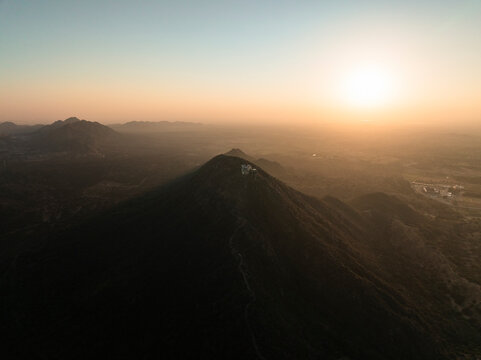 Aerial view of serene sunset over Shree Savitri Mata Temple with majestic mountains in the background, Pushkar, Rajasthan, India.