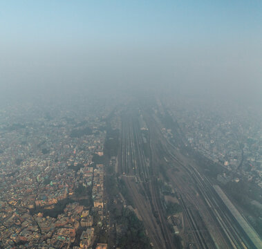Aerial view of a bustling train station amidst a dense urban landscape with modern buildings, Pahar Ganj, New Delhi, India.