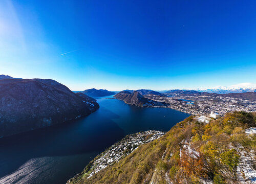 Aerial view of beautiful Lake Lugano surrounded by majestic mountains on a clear sunny day, Bre sopra Lugano, Switzerland.