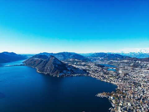 Aerial view of picturesque cityscape with tranquil Lake Lugano and serene Swiss Alps, Bre sopra Lugano, Switzerland.