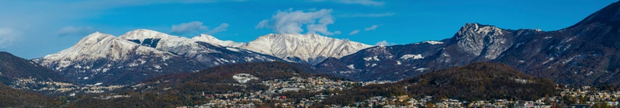 Aerial view of breathtaking snowy mountains and serene Lugano City, Kanton Tessin, Switzerland.