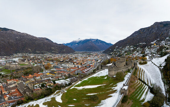 Aerial view of the historic castle of Montebello surrounded by snow-capped mountains and a picturesque town, Bellinzona, Switzerland.