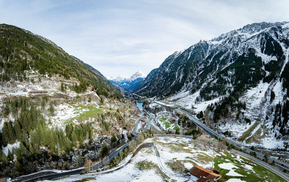 Aerial view of scenic Highway A2 surrounded by majestic mountains and a tranquil valley with snow-covered peaks, Wassen, Switzerland.