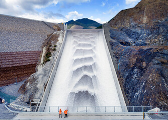Aerial view of a scenic dam with a spillway and flowing water surrounded by mountains, Nelson, New Zealand.