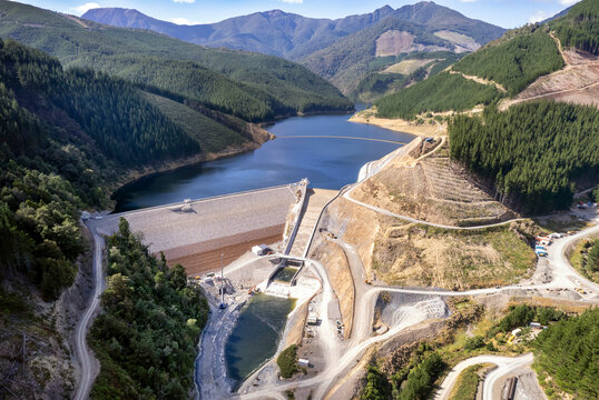 Aerial view of a majestic dam and serene lake surrounded by mountains and forests, Nelson, New Zealand.