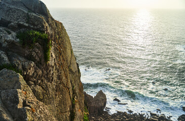 An absolutely stunning seaside landscape featuring rugged cliffs and shimmering ocean waves visible...