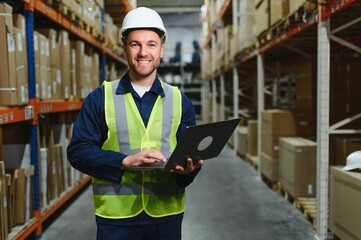 Warehouseman checking delivery, stock in warehouse on laptop. Warehouse manager using warehouse management software, app.