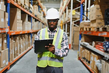 Portrait of african american warehouseman with clipboard checking delivery, stock in warehouse....