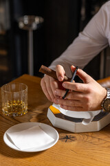 Close up of man hands cutting cigar
