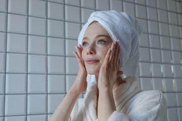 A woman is seen performing her complete skincare routine in the serene ambiance of her bathroom