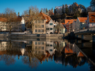 Fototapeta premium Historic Town Of Landsberg Am Lech In Bavaria: Winter Charm With A Frozen River And Colorful Houses Under A Clear Blue Sky