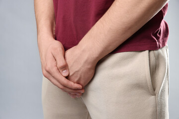 STD (sexually transmitted diseases). Man suffering from symptoms on grey background, closeup