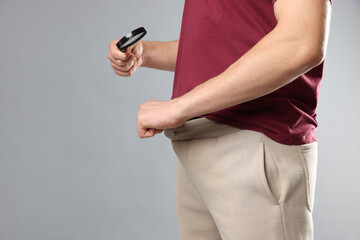STD (sexually transmitted diseases). Man examining intimate area with magnifying glass on grey...