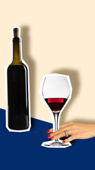 Cut-out wine bottle and glass of red wine with hands elegantly holding the glass against minimalist background in light beige and blue tones. Creative design. Concept of drinks, party, celebration