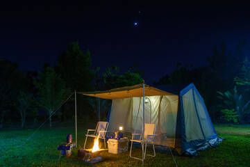 Camping tents at night, vintage cabin tents, antique gas lamps, retro chairs, and a group of...