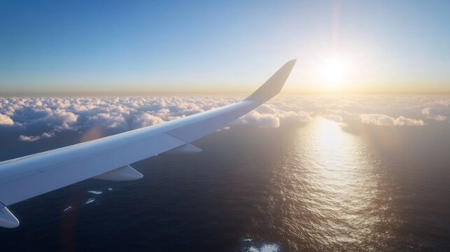 Aerial view of clouds and ocean during sunset from an airplane window.