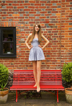 Teenage Girl Standing on Red Bench
