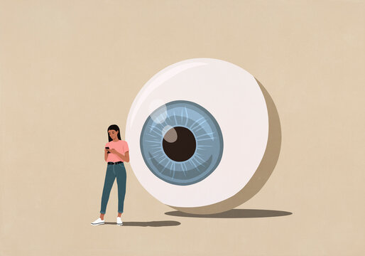 Large surveillance eyeball looking over shoulder of young woman texting with smart phone
