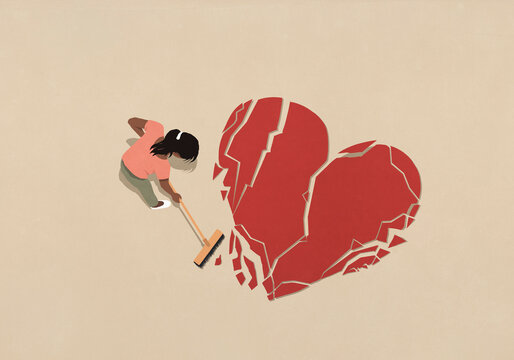View from above woman with broom sweeping broken heart
