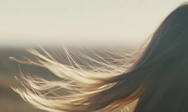Whispers of Freedom: A woman's flowing blonde hair, seemingly caught in a gentle breeze, captures a sense of liberation and carefree joy. The warm light creates an aura of mystery.