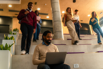 University professor working with laptop while students walking up stairs