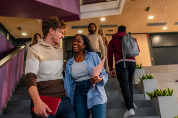 University students walking and talking on stairs in modern building