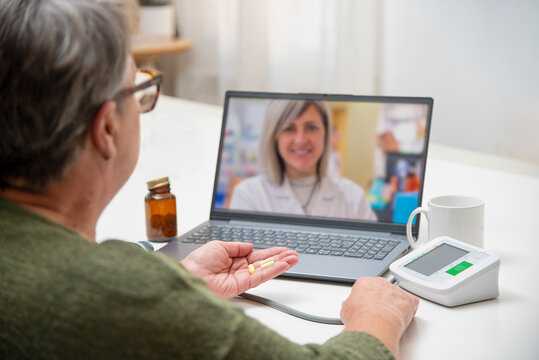 Senior woman using laptop for online medical consultation with doctor at home - Powered by Adobe