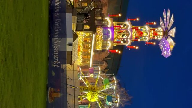 MANNHEIM, GERMANY - NOVEMBER 30, 2024 - Festive Christmas market at night with colorful lights and carousel in Germany. Vertical video