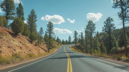 Naklejka premium Winding road leading through a scenic wooded landscape under clear sky