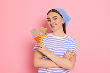Portrait of young decorator with putty knife and brush on pink background