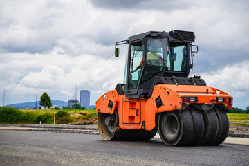 Asphalt compaction roller on a highway construction site during a sunny day. Process of asphalt pavement.