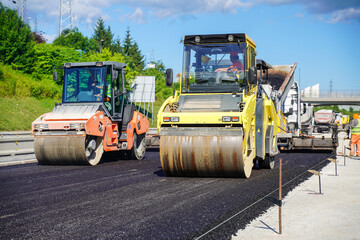 Asphalt compaction roller on a highway construction site during a sunny day. Process of asphalt pavement.