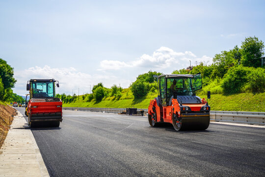 Asphalt compaction roller on a highway construction site during a sunny day. Process of asphalt pavement. Freshly paved road.