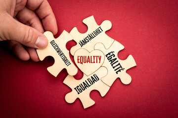 EQUALITY. Spanish Swedish French German. Wooden puzzle in the shape of a heart on a red background