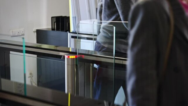 Passing through a turnstile into an office building. Office workers enter and exit through a modern turnstile, using a key card to enter.