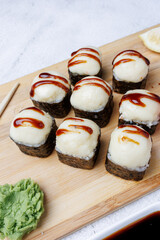 sushi rolls with baked cheese, unagi sauce, sesame, lemon, soy sauce, ginger, wasabi, sushi set on a light background, still life, food, Japanese cuisine, flatlay