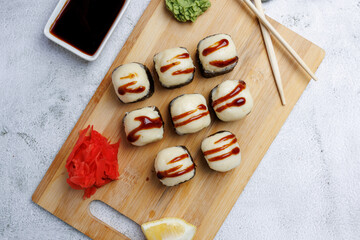 sushi rolls with baked cheese, unagi sauce, sesame, lemon, soy sauce, ginger, wasabi, sushi set on a light background, still life, food, Japanese cuisine, flatlay