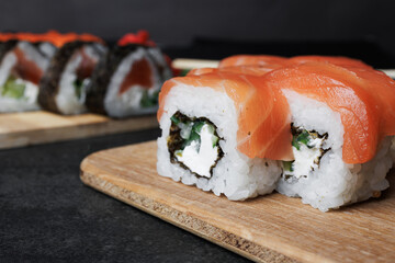 set of sushi rolls with salmon, cucumber, avocado, flying fish caviar, on a black background, soy sauce, unagi, lemon, ginger, wasabi, food, still life, Japanese cuisine