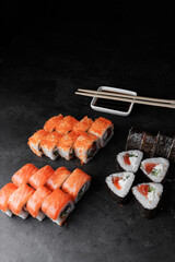 set of sushi rolls with salmon, cucumber, avocado, flying fish caviar, on a black background, soy sauce, unagi, lemon, ginger, wasabi, food, still life, Japanese cuisine