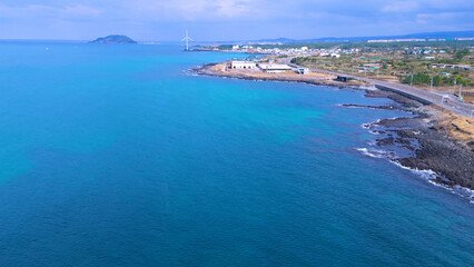 Obraz premium A drone shot of the beautiful sea scenery of Jeju Island, Korea, which boasts a green emerald cleanliness. Best healing trip. Harmony of basalt and waves