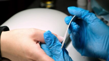 Skilled technician files and shapes nails with care, showcasing expert manicure techniques in a cozy local salon environment.