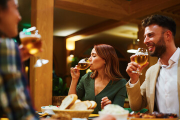 Group of friends drinking beer and enjoying meal together at restaurant